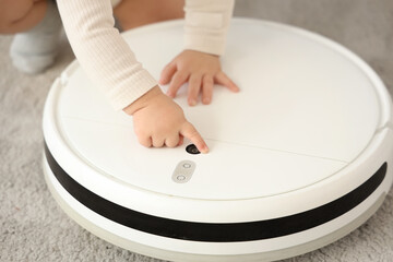 Cute little baby with robot vacuum cleaner at home, closeup