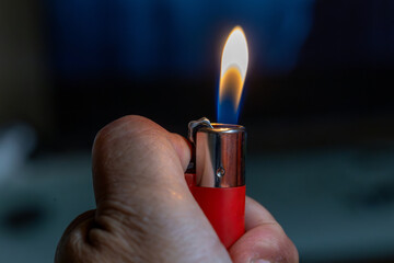 Mano sujetando mechero rojo encendido