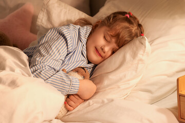 Adorable little girl with teddy bear sleeping in bed