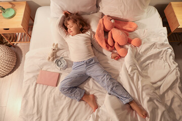 Adorable little girl with plush toys, book and alarm clock sleeping in bed - obrazy, fototapety, plakaty