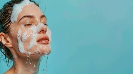 Portrait photo of a white woman with clear skin and eyes closed with soap suds on her face on a solid light blue background