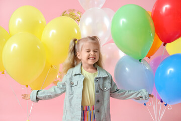 Happy little girl with colorful balloons on pink background