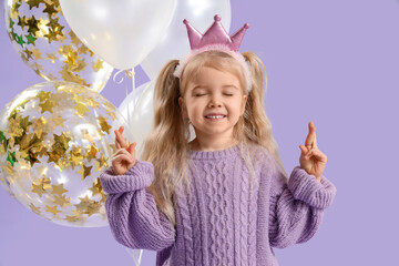 Happy little girl with crossed fingers  and balloons on lilac background
