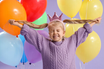 Happy little girl with closed eyes and balloons on lilac background