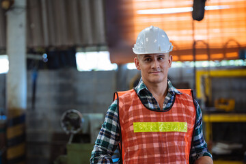 Portrait of male foreman factory wearing hardhat looking at camera standing at the industry factory. Construction worker or builder career in positive attitude