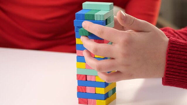 Strategic Move. player deftly removes a colorful block from a vibrant Jenga tower. illustration themes of strategy, risk-taking, and leisure activities