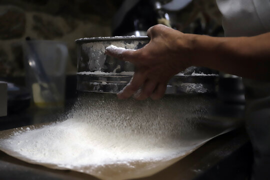 repostera tamizando harina para hacer pan