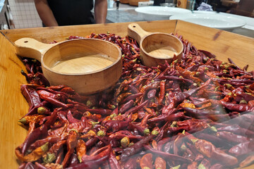 A wooden tray in a restaurant holding a heap of Chinese dry chili and Sichuan peppercorns.