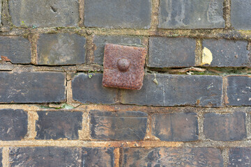old brick wall with rusty old metal pin
