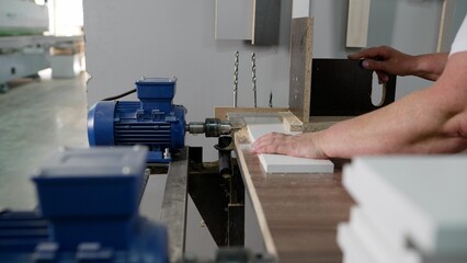Close-up of a hole in a wood panel using a drill press. A drilling machine makes a hole in an MDF...