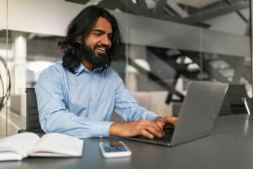 Smiling professional typing on a laptop