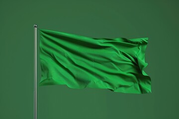 A green flag is blowing in the wind. The flag is green and has a white stripe