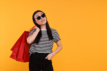 Smiling woman with shopping bags on yellow background. Space for text