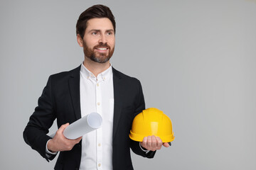 Architect with draft and hard hat on gray background, space for text