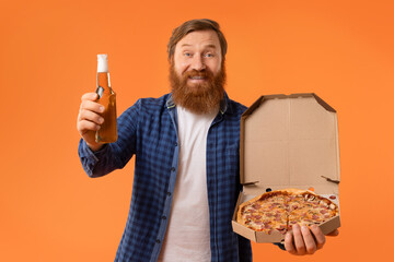 Redhaired bearded guy holding pizza box and beer bottle, studio