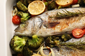 Delicious fish with vegetables and lemon in baking dish, closeup