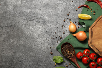 Cooking concept. Wooden cutting board and different products on grey textured table, flat lay. Space for text