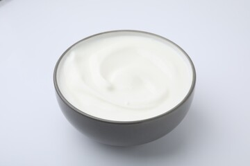 Delicious natural yogurt in bowl on white background