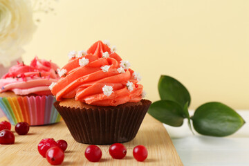 Delicious cupcake with bright cream and flowers on white table