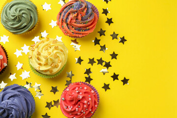Delicious cupcake with bright cream and shiny confetti on yellow background, flat lay. Space for...