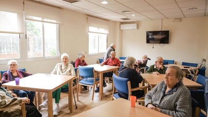 Elderly men and women sitting in nursing home canteen - obrazy, fototapety, plakaty