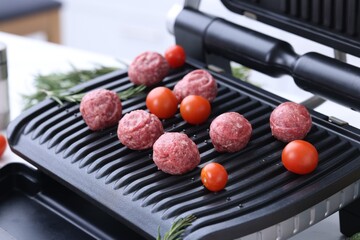 Meatballs, tomatoes and rosemary on electric grill, closeup