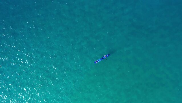 Ocean, relax and people paddle boarding from drone with blue water, freedom and tropical holiday. Fun, sports and adventure for couple of friends, paddleboard or travel vacation at sea in aerial view