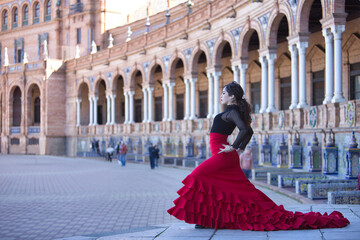Young, beautiful, brunette woman in black shirt and red skirt, dancing flamenco in the beautiful...