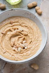 Grey bowl with peanut butter or paste made from ground, dry-roasted peanuts, vertical shot, middle closeup