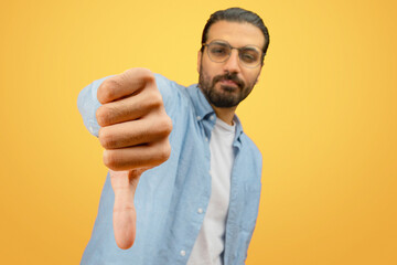 Man with thumbs down gesture on yellow