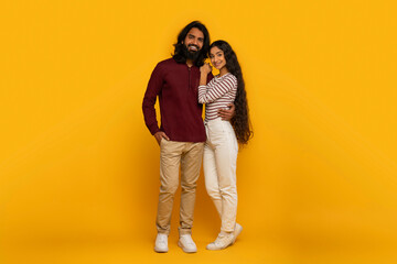 Man and woman point to space on yellow background