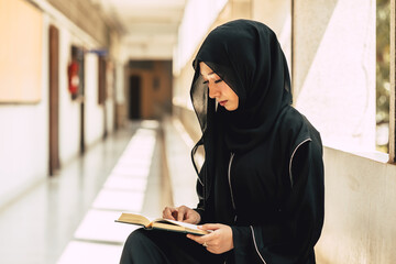 Young teen muslim niqab woman reading the Quran and faith The Holy Al Quran in University building....