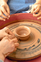 Master class on clay modeling on a potter's wheel. Tutor teaching a child