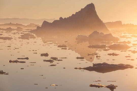 Floating giant iceberg in orange hues of midnight sun at Ilulissat Icefjord in Greenland