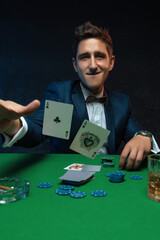 Poker player throwing a pair of aces at table in casino.