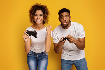 Gaming couple showing enthusiasm and fun on yellow background © Prostock-studio
