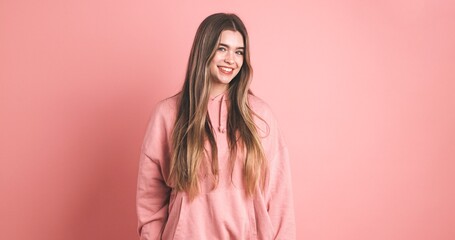 Fototapeta premium Happy woman with long hair smiling in pink studio