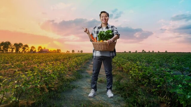 Full Body Of Asian Male Farmer With Vegetable Basket Smile Pointing To The Side While Standing In Field