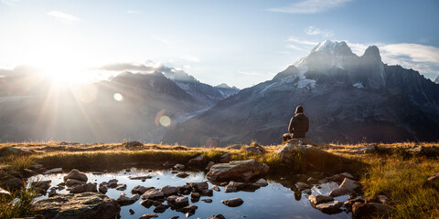 Panoramic view of a seated person watching the sunrise in mountains