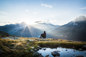 Seated person watching the sunrise in mountains
