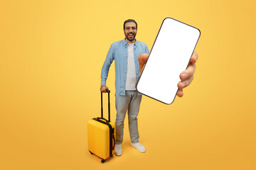 Happy man with luggage presenting phone