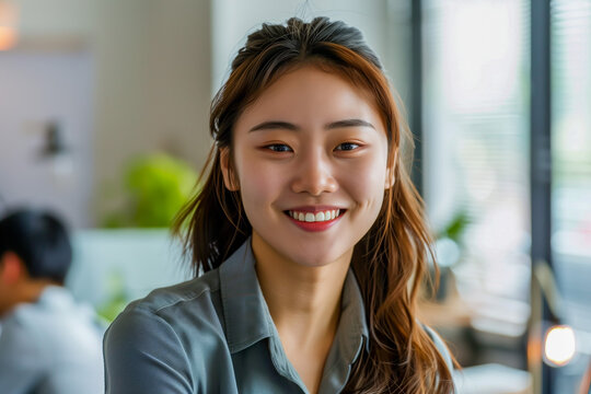 Young smiling beautiful asian company employee in the office. Closeup portrait of happy woman.