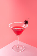 Tropical cocktail with cherry on vivid pink background. Minimal summer drink composition.