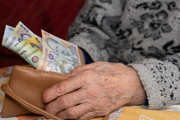 An old woman takes out a small amount of Romanian lei from her wallet, Financial concept, Rising cost of living and difficulties of retirees in Romania - 772236279