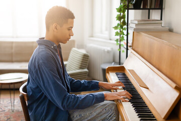 Young musician practicing piano in a peaceful room - obrazy, fototapety, plakaty