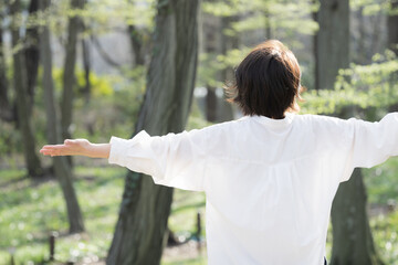 Back view of a woman taking a deep breath in the forest