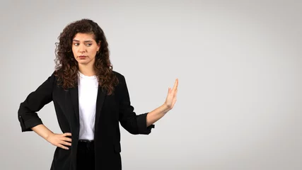 Fototapeten Skeptical businesswoman with hand gesture © Prostock-studio