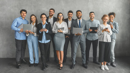 Group of smiling professionals with laptops in modern office