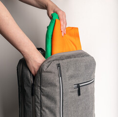 Hands packing clothes into backpack, bag