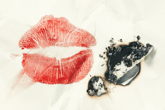 Smudged lip print and an extinguished cigarette with ashes on crumpled white paper. Kiss lips lipstick mark.  Lipstick kiss. Shallow depth of field. Toned image